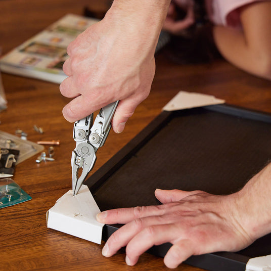 Translation missing: fr.Someone using the pliers on a Leatherman Surge to fix a picture frame