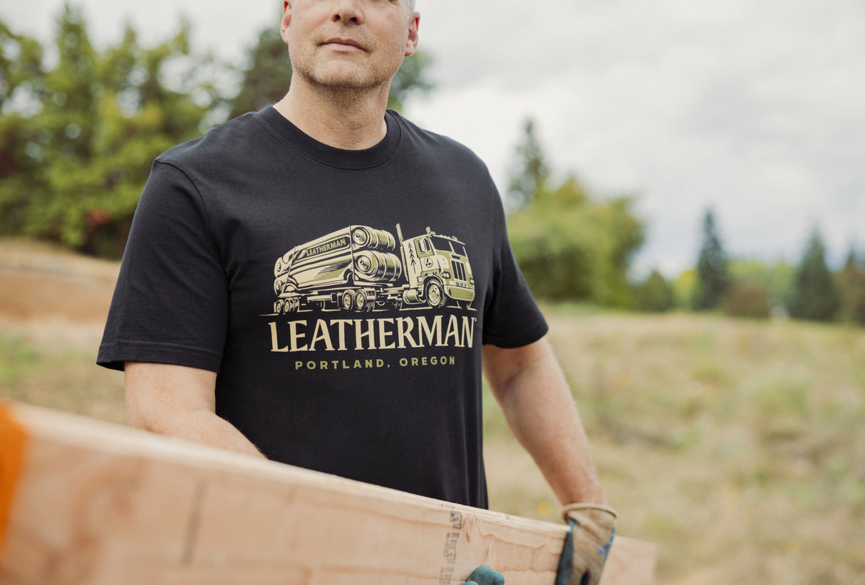 Translation missing: en.A person wearing a black Leatherman Timber Tee carrying a wooden board outdoors