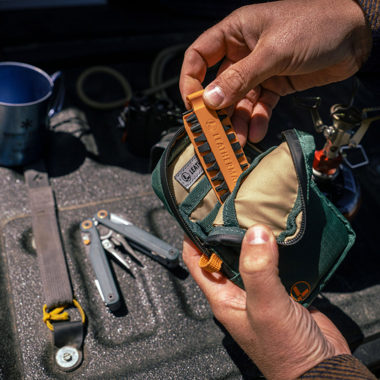 Translation missing: fr. A person placing Orange Leatherman Bit Kit into Tool Pouch