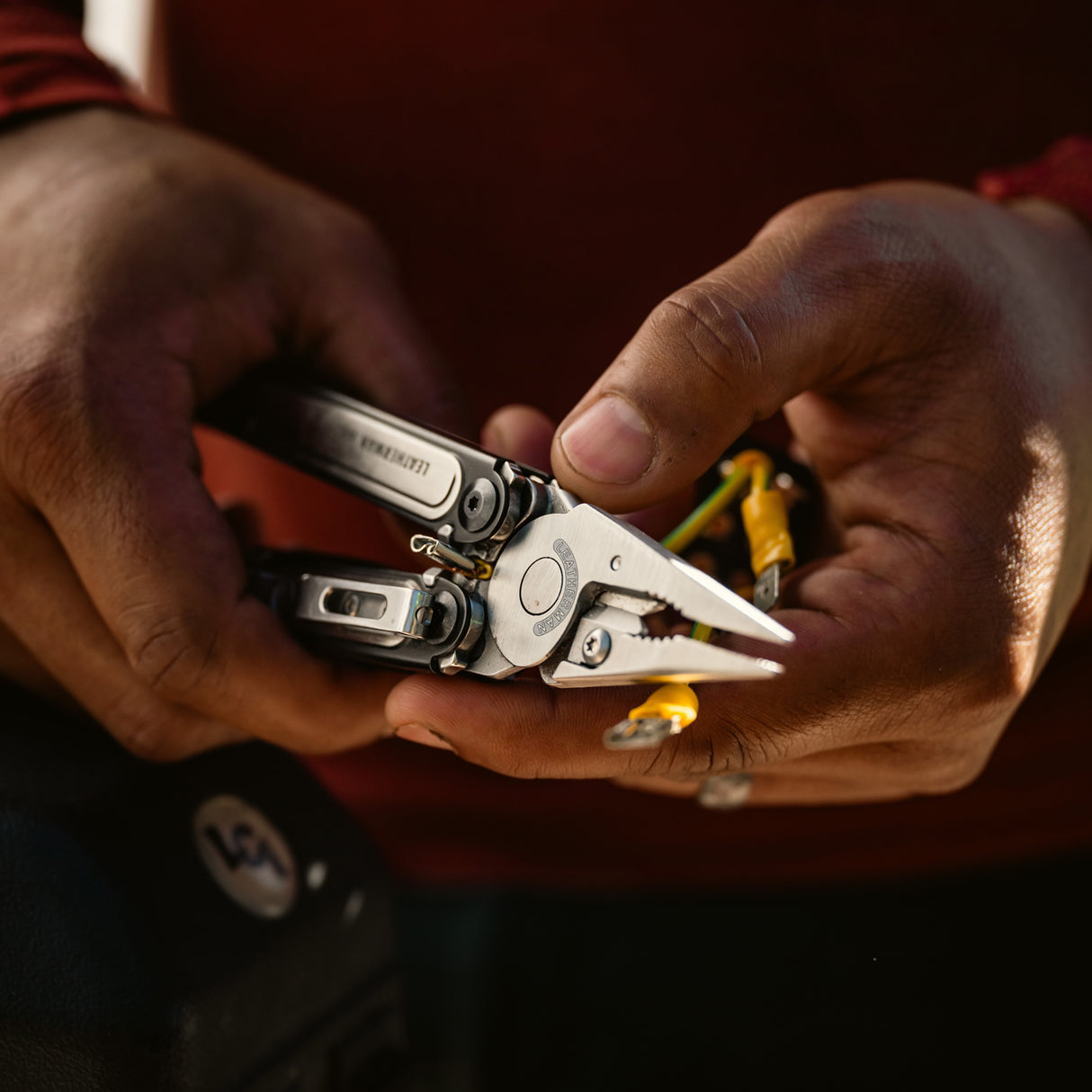 Translation missing: fr.Person cutting rope with a Black DLC stainless steel Leatherman ARC® in a grassy outdoor setting