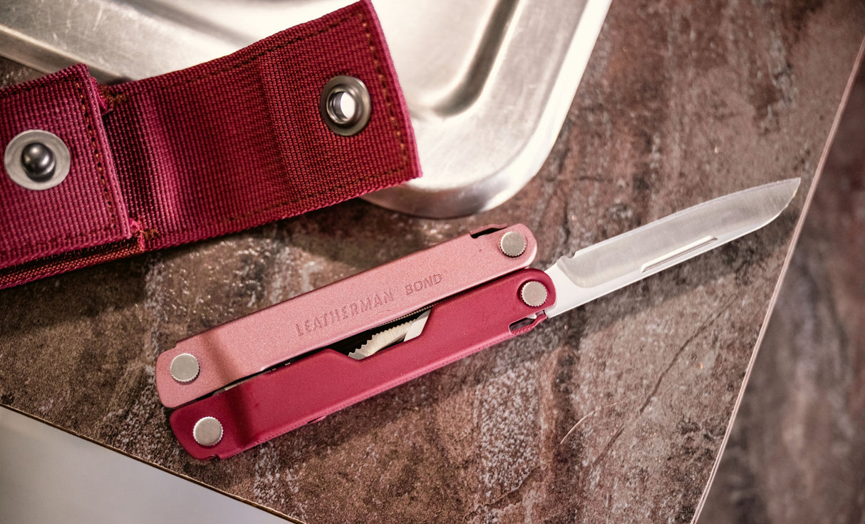 Translation missing: en.Heathered Cranberry Bond open showing knife blade and a Heathered sheath that is open next to a sink on the countertop
