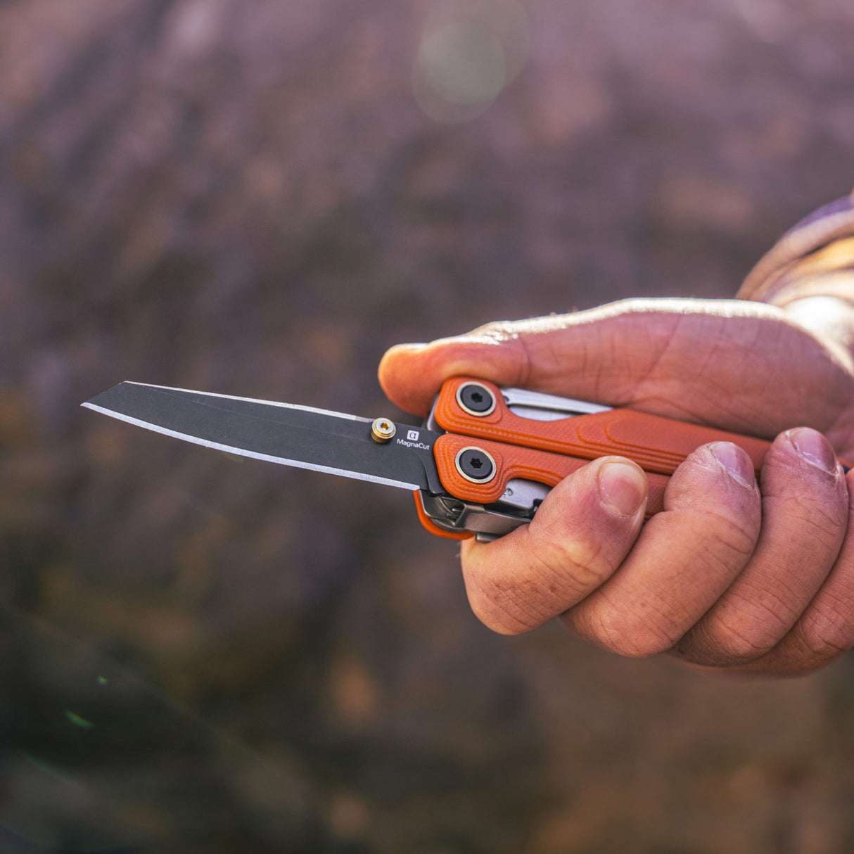 Translation missing: fr.Canyonland Leatherman Wave® Alpha multi-tool held in hand, showcasing its sleek design and sharp blade against a natural background