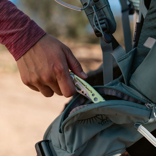Translation missing: fr.Person putting a closed Skeletool KB into a backpack