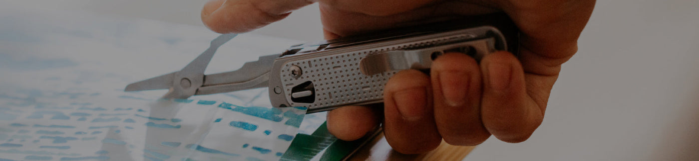 Translation missing: fr.Hand holding Leatherman Free T2 with scissors opened, being used to cut paper