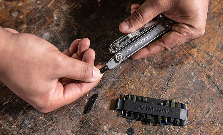 Translation missing: fr.Man replacing a bit from Leatherman Bit Kit on Leatherman Curl over wood table