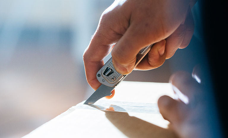 Translation missing: en.Man using box opener on Leatherman T2 to open brown box