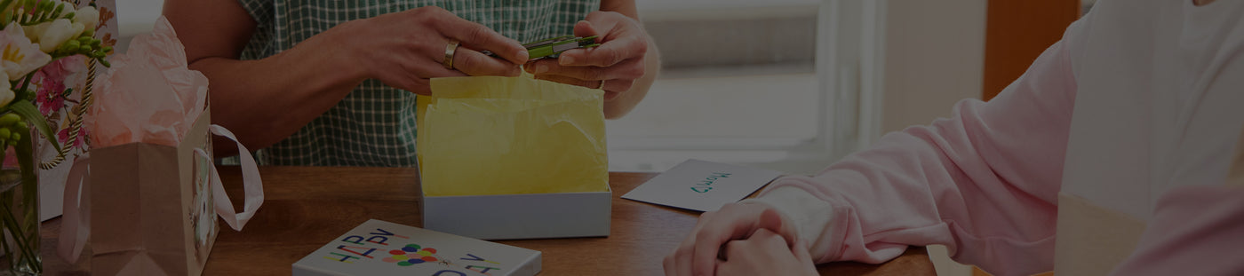 Translation missing: en.A mother opens Leatherman gift from son sitting at a table, capturing a moment of happiness and connection between them