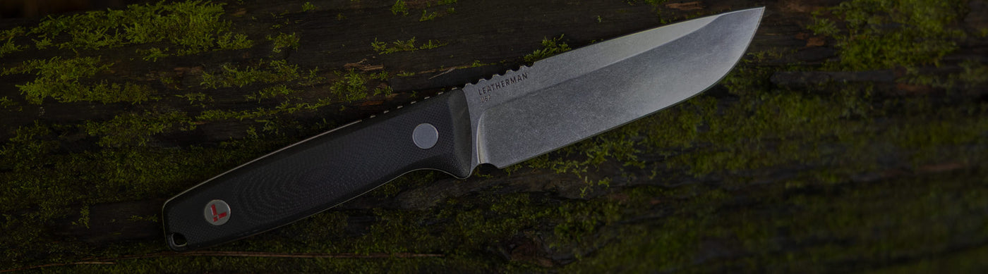 Translation missing: en.Leatherman Trac in soft focus, placed on a mossy log, showing off the state of the art Magnacut steel blade and g10 handle