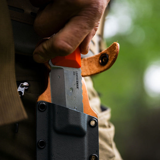 Translation missing: en.Orange Pop Leatherman Pioneer showing off the bright orange G10 handle being pulled from a premium sheath