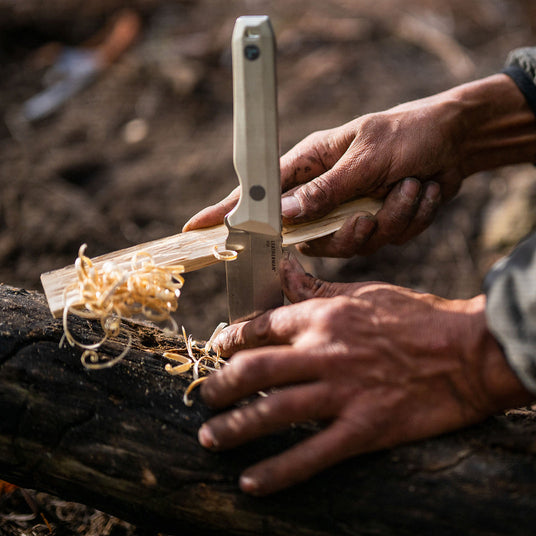 Translation missing: en.Alpine Leatherman Pioneer planted in a log and braced by rough hands to help make feather stick tinder