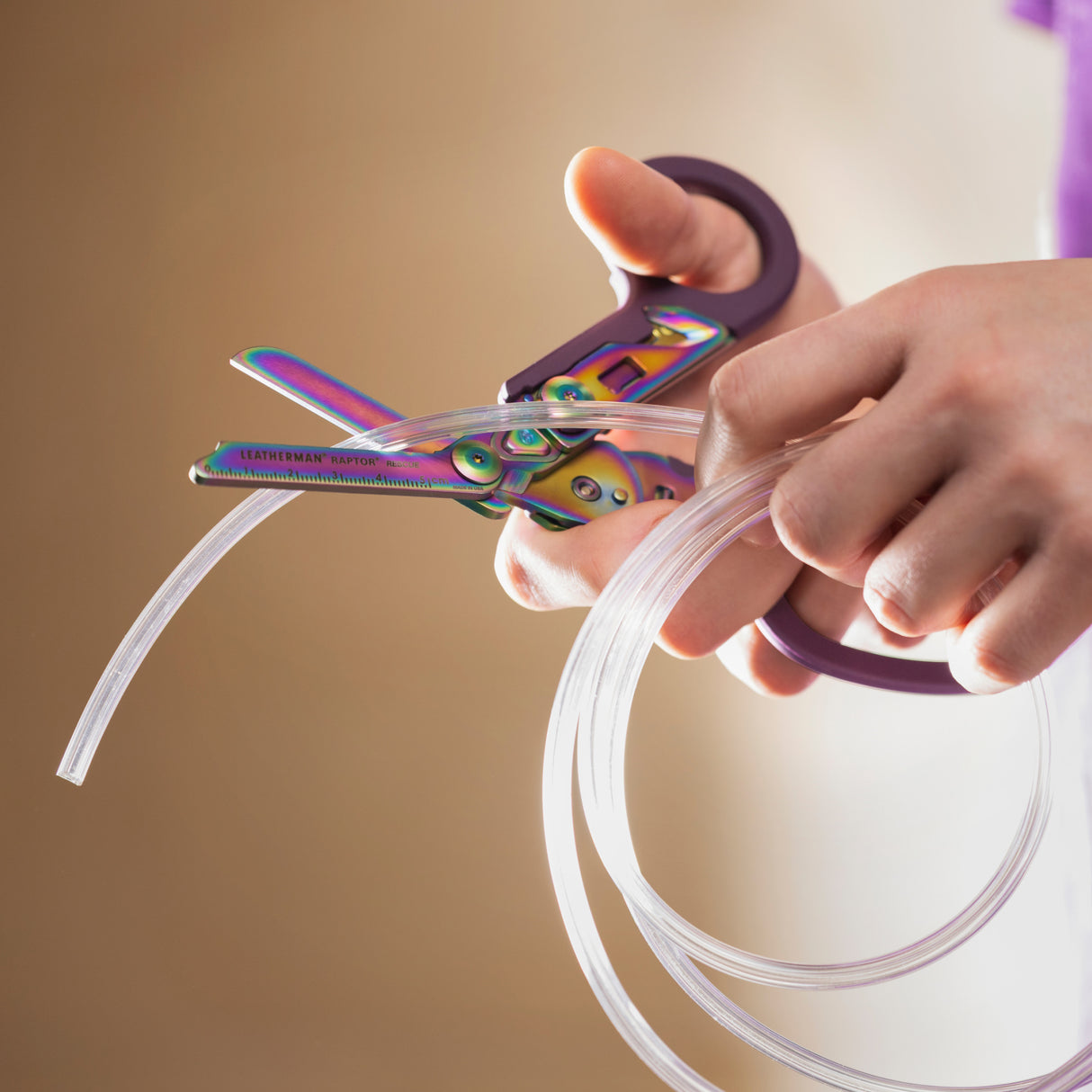 Translation missing: en.Hands using a Rainbow Raptor® Rescue tool to cut clear flexible tubing