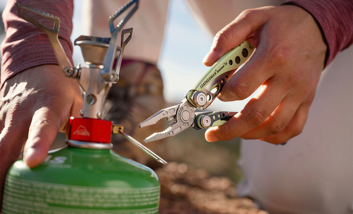 Translation missing: en.Hands using a Verdant Skeletool® CX multitool pliers to adjust a small camping stove on a green fuel canister