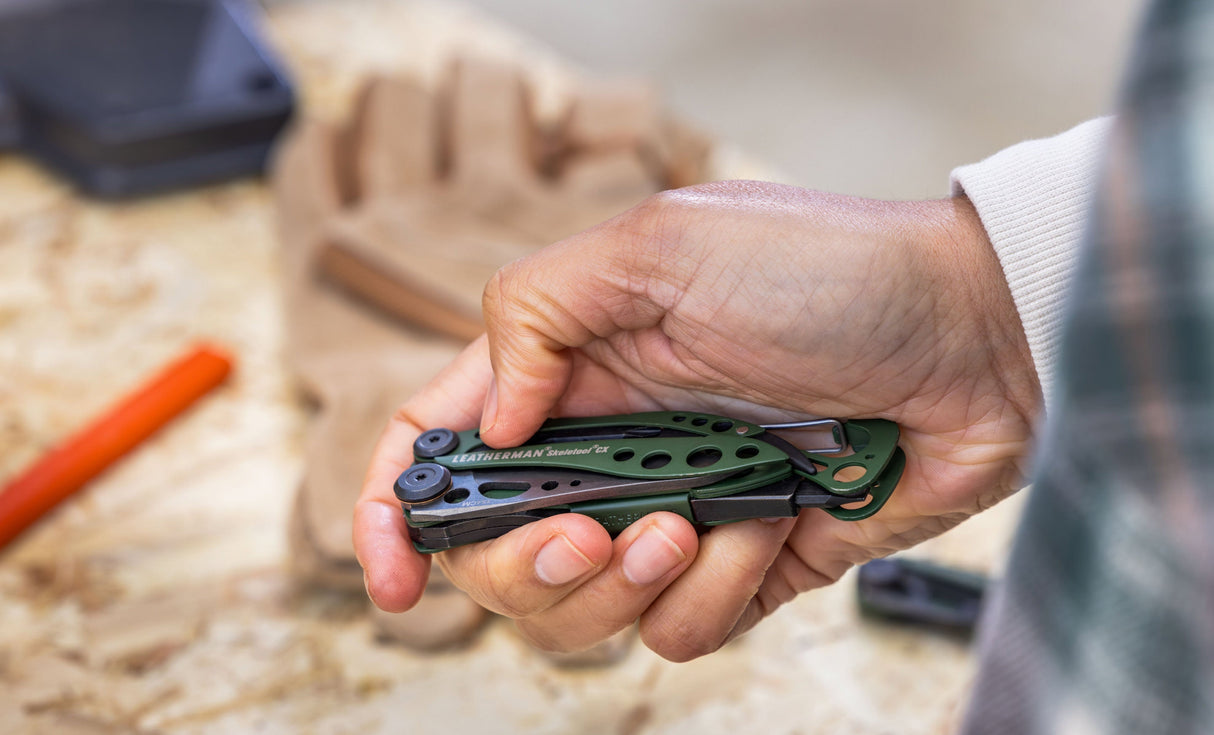 Translation missing: en.Hand holding a folded OD Green Skeletool® CX multitool with cutout handle and pocket clip