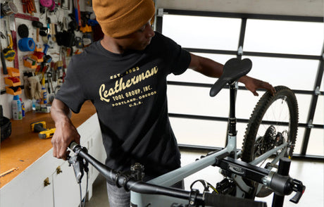 Translation missing: fr.Person assembling a bicycle in a workshop wearing a black Leatherman Vintage Tee