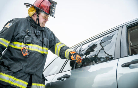 Firefighter using a Raptor glass breaker to break a car window.