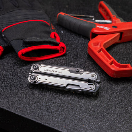 Leatherman Arc, black and red safety glove and small tool featuring a prominent red handle.