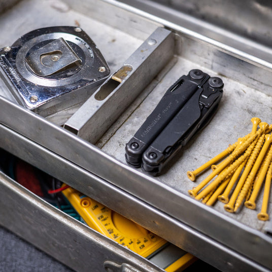 Closed Surge laying on a metal tray next to a tape measure and nails