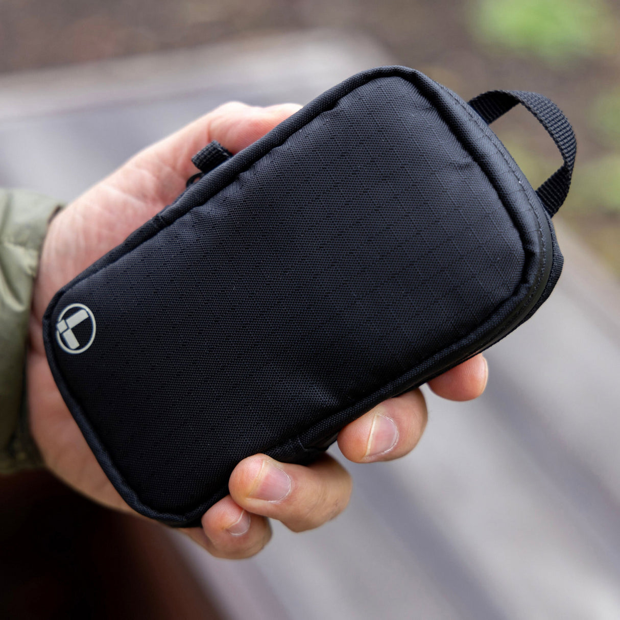 Translation missing: en.A person holds a compact black Leatherman Tool Pouch with a stitched logo and top loop, showcasing its durable construction and convenient size for everyday carry