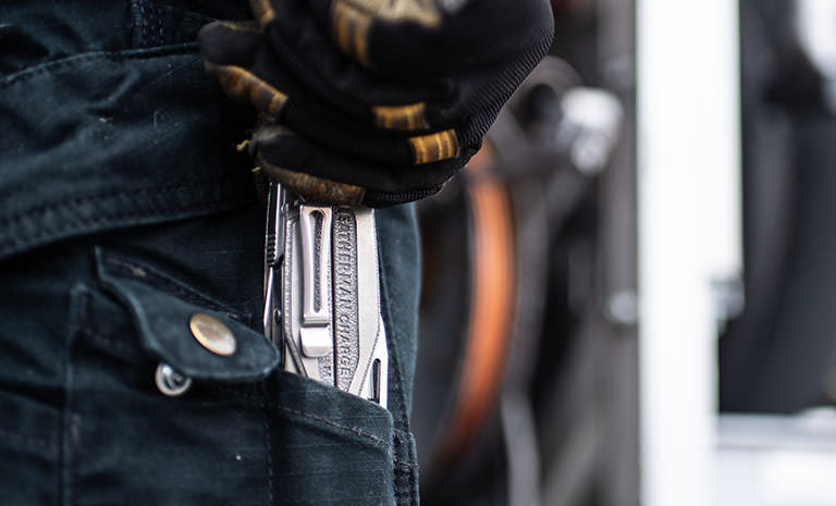 Translation missing: fr.Man with dirty black and yellow gloves pulling Charge+ TTI out of back jean pocket