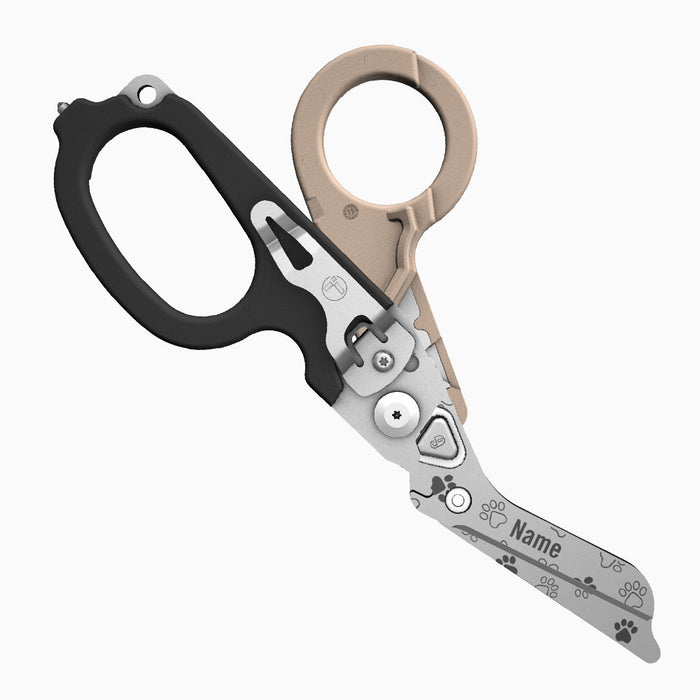 Translation missing: fr.A two-tone tan-and-black-handled Leatherman Raptor Rescue tool with pawprints laser printed on the blade, which is personalized with the placeholder “Name.”