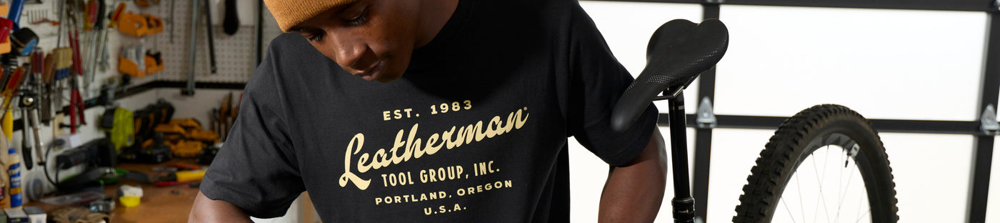 Translation missing: fr.Man wearing a black Leatherman Vintage Tee in a workshop setting