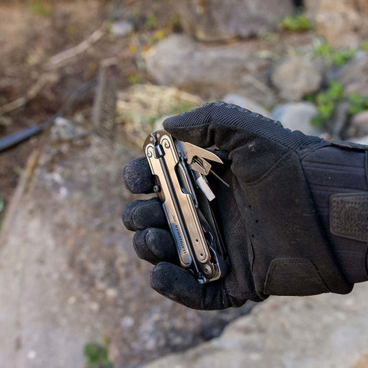 A gloved hand holding an ARC with some included tools showing.