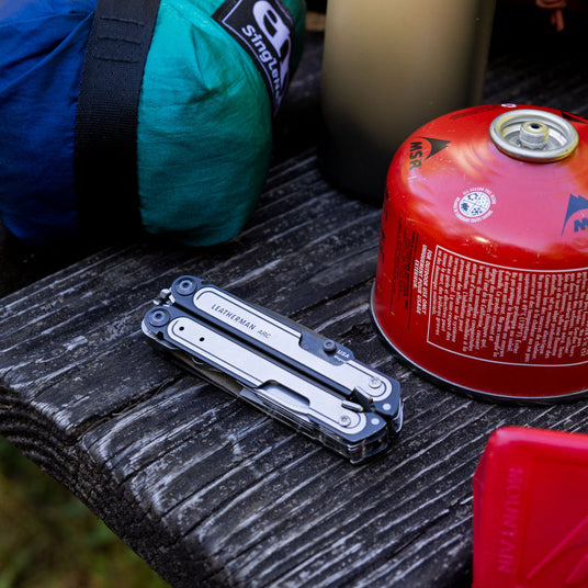 A closed ARC lying on a bench table next to camping supplies.