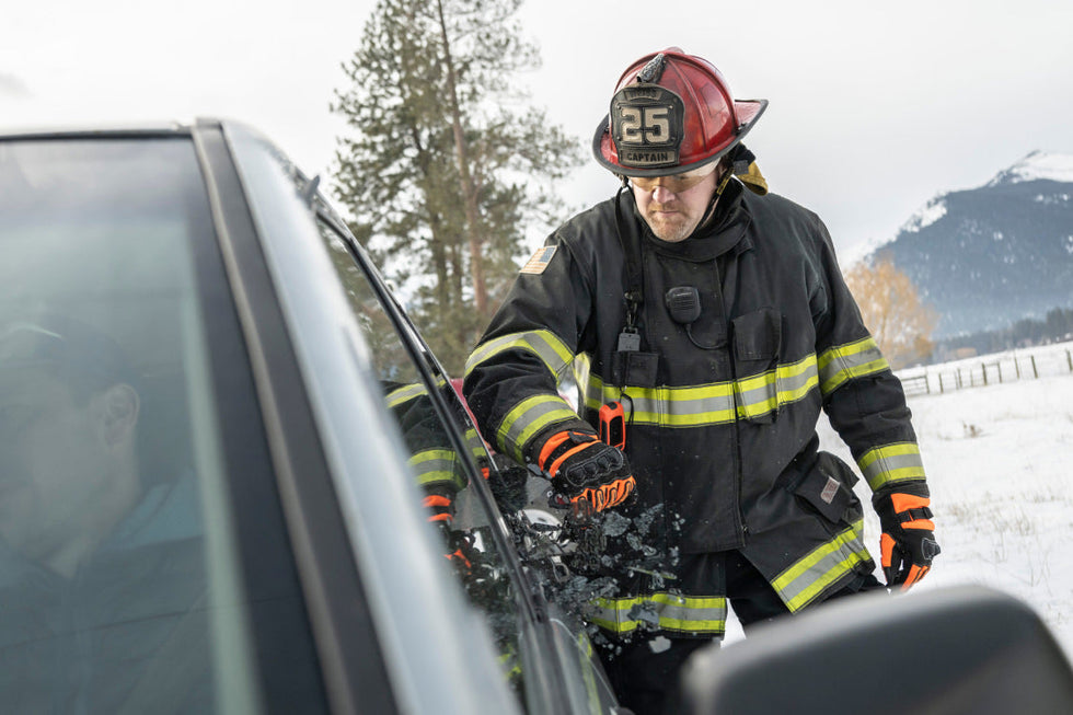 Firefighter assisting person stuck inside car.