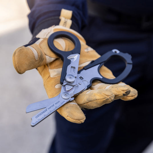 Person with yellow gloves holding opened Leatherman black Raptor shears.