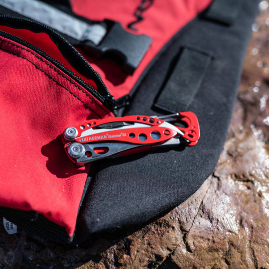 Closed Leatherman red Skeletool RX on top of red and black backpack.