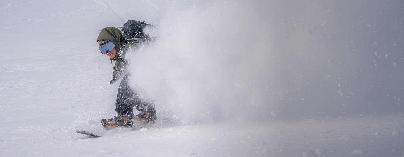Translation missing: en.Snowboarder carving through fresh powder in a winter wonderland, showcasing dynamic movement and winter sport excitement