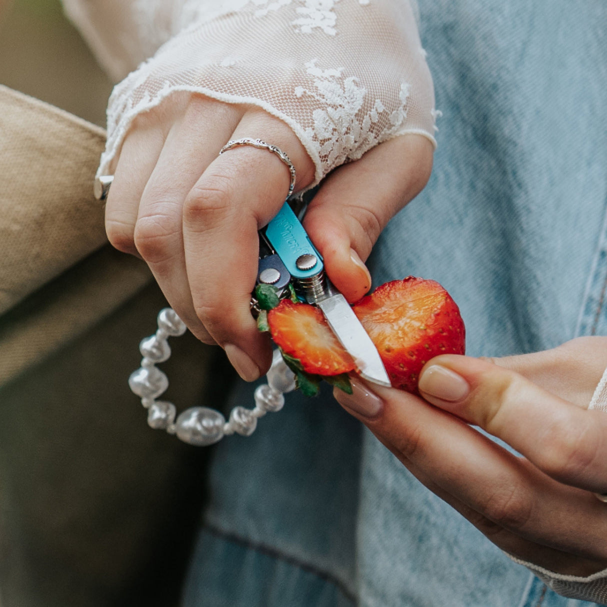 Translation missing: en.Person using the knife on a Leatherman Micra® in Lavender Mist color to slice the top off of a strawberry