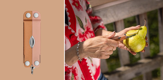 Translation missing: en.A person using the knife on a Ginger Peach Micra® multitool to cut into a pear, showcasing a stylish design and practical functionality