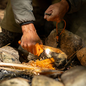Translation missing: en.A person holds a Leatherman Orange pop Pioneer to a piece of wood, attempting to start a fire
