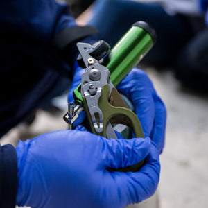Translation missing: en.Person wearing blue gloves using the oxygen tank wrench on a Leatherman Woodland Raptor® Rescue to open an oxygen tank