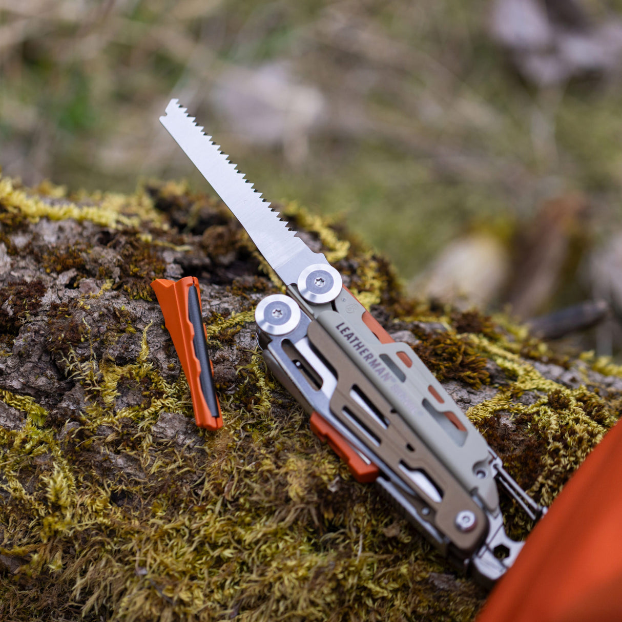 Translation missing: en.Tundrascape Leatherman Signal® laying on a mossy log, showcasing the ferro rod and saw