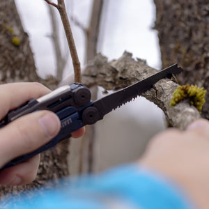 Translation missing: en.A person using the saw on a Nocturnal Leatherman Signal® to cut a branch