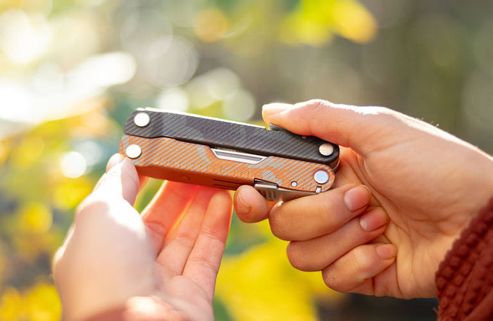 Translation missing: en.Burnt Sienna Leatherman Rebar customized with a camouflage design held in hands outdoors, showcasing its sleek design and vibrant colors