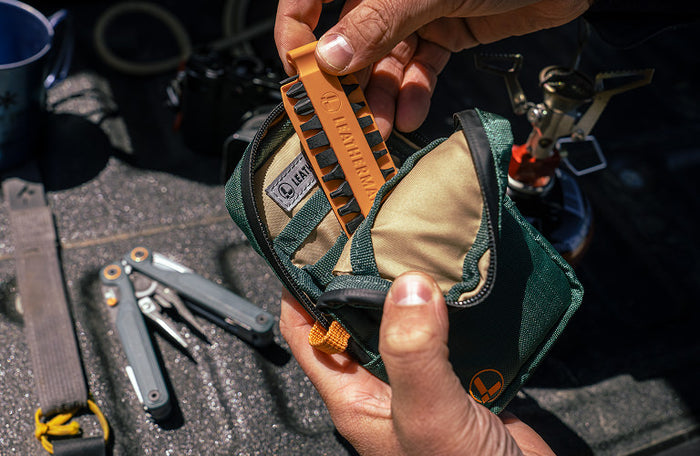 Translation missing: en.Person holding Hunter Leatherman® Tool Pouch with an orange Bit Kit, showcasing tools and outdoor setting