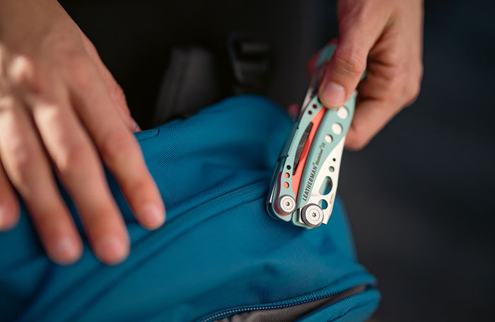 Translation missing: en.Person retrieving a Paradise Leatherman Skeletool® CX from a teal backpack