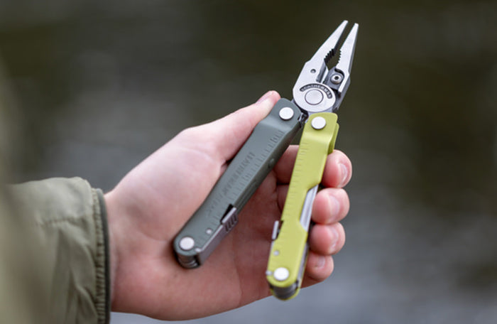 Translation missing: en.Person holding a Mossy Slate Leatherman Rebar® multi-tool with pliers, showcasing its versatility and design