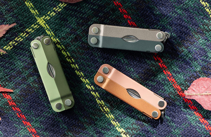 Translation missing: en.Three Micra® multitools in Cardamon, Ginger Peach, and North Star colors displayed on a plaid background with autumn leaves